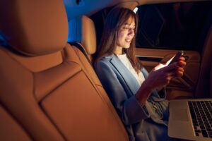 Smiling businesswoman using mobile phone in car